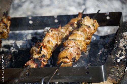 Juicy shish kebab grilling on skewers over hot coals, ready for a delicious summer barbecue. photo