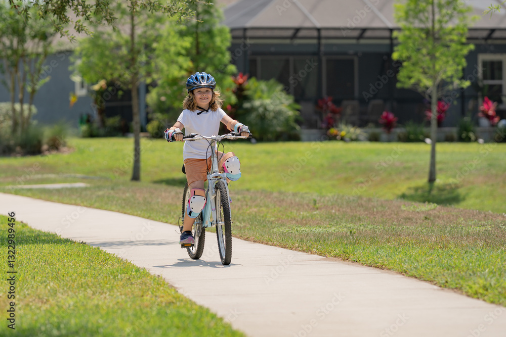 Fototapeta premium Kid riding bike in a helmet. Child with a childs bike and in protective helmet. Articles on safety and kid sports and activity. Happy kid boy having fun in summer park with a bicycle.