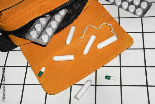 Feminine hygiene products and medication from a vibrant orange bag. photo