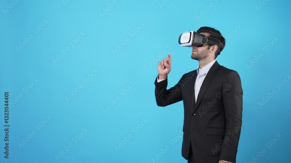 Professional businessman pointing hand and checking financial data while wearing VR glasses. Smart project manager moving hand while planning marketing strategy by using augmented reality. Apparatus. Professional businessman pointing hand and checking financial data while wearing VR glasses. Smart project manager moving hand while planning marketing strategy by using augmented reality. Apparatus.