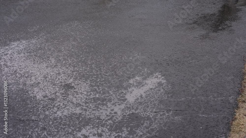 Invisible danger black ice covering the asphalt, creating hazardous driving conditions in winter. Wide view