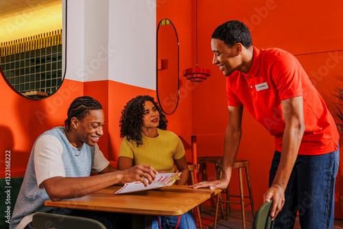 Couple ordering food in restaurant with waiter recommending dishes