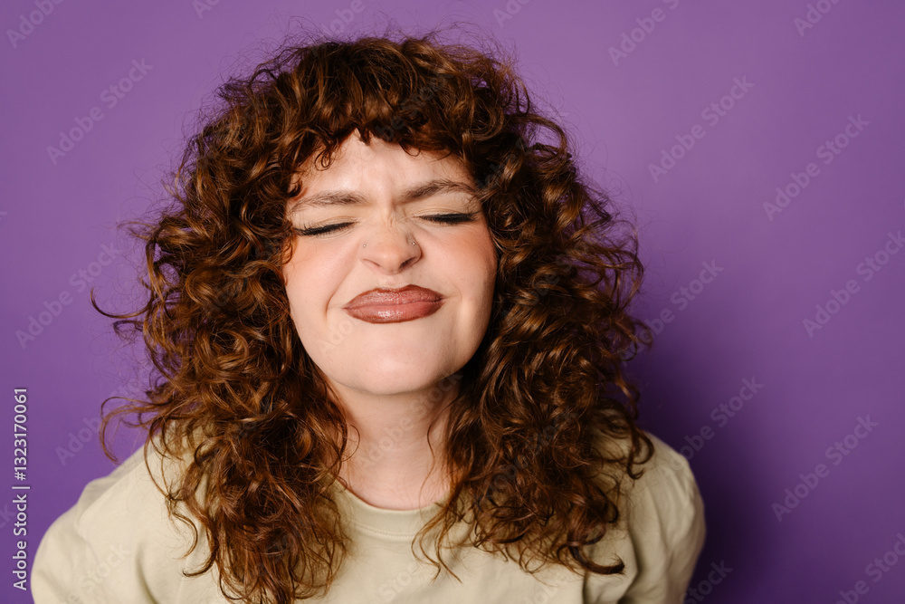 Curly-Haired Woman Makes Playful Face Against Purple Background Curly-Haired Woman Makes Playful Face Against Purple Background