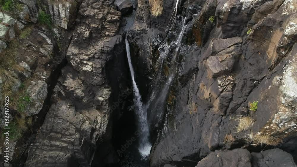 Looking down rugged stone cliffs, waterfalls drain into deep gorge Looking down rugged stone cliffs, waterfalls drain into deep gorge