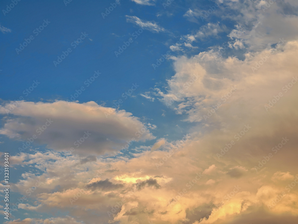 A captivating skyscape filled with fluffy clouds. Some clouds are white, while others are illuminated with a warm, golden sunlight, creating a beautiful contrast against the blue sky. A captivating skyscape filled with fluffy clouds. Some clouds are white, while others are illuminated with a warm, golden sunlight, creating a beautiful contrast against the blue sky.