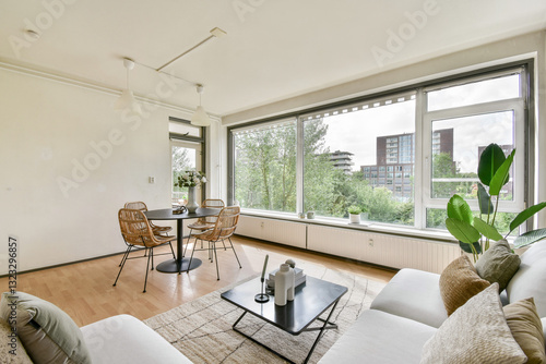 A stylish modern living room featuring a cozy seating area, a chic coffee table, and large windows offering a view of city greenery. Perfect for relaxation and socializing.