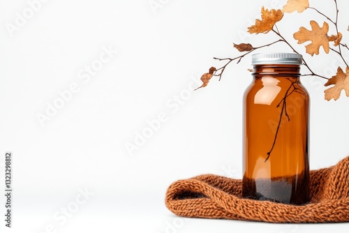 Decorative amber glass bottle with dried autumn leaves arranged beside soft fabric creating a warm cozy interior decor composition with natural elements and rustic charm