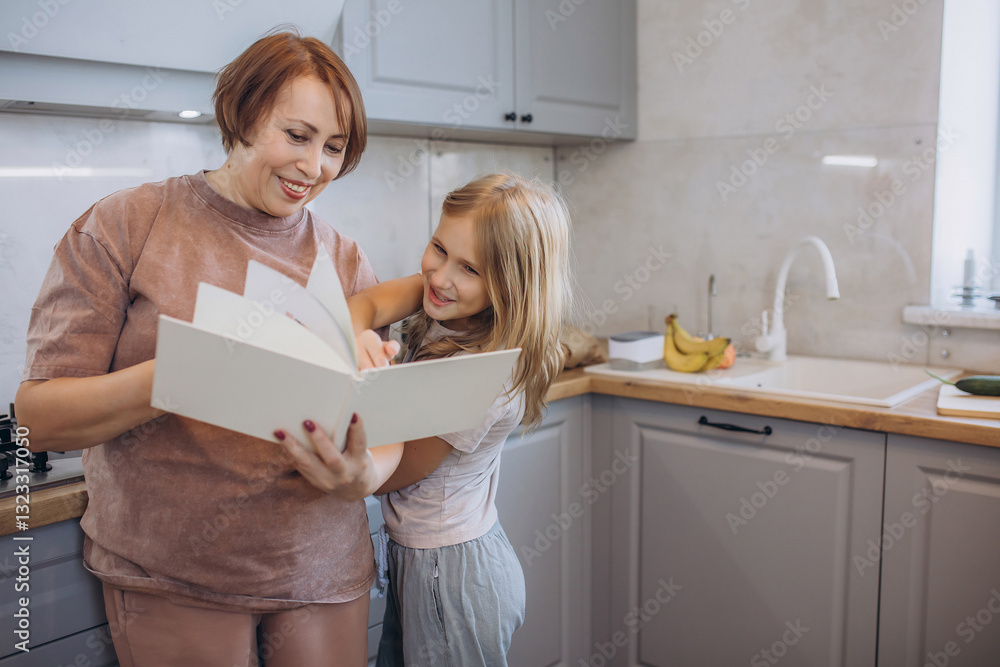 Grandma and granddaughter are in the kitchen reading recipes and learning how to cook together Grandma and granddaughter are in the kitchen reading recipes and learning how to cook together