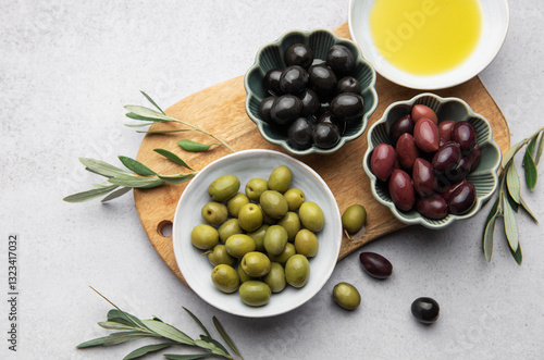 Variety of olives, olive oil, and olive branches served on a wooden board
