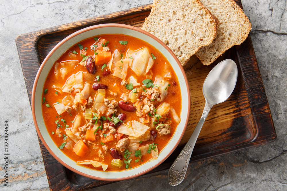 Italian sausages cabbage tomato soup with vegetables close-up in a bowl on the table. Horizontal top view from above