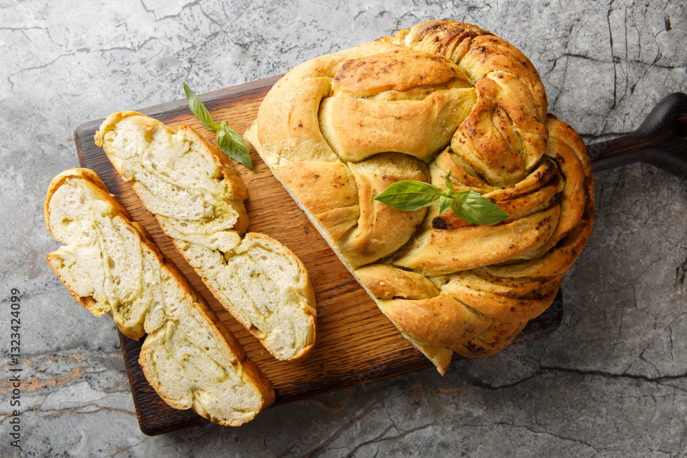 Italian homemade pesto bread braid close-up on wooden board on table. Horizontal top view from above
