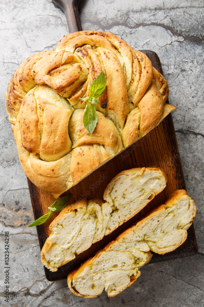 Delicious Pesto Bread is a soft and fluffy homemade bread that has swirls of fragrant basil pesto throughout closeup on the wooden board on the table. Vertical top view from above
