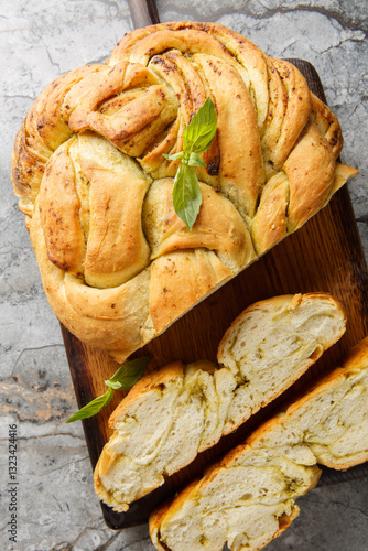 Obraz na płótnie Mediterranean spicy basil pesto braided bread close-up on wooden board on table. Vertical top view from above w salonie
