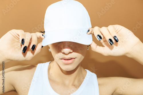 Androgynous person adjusting blank white cap in studio