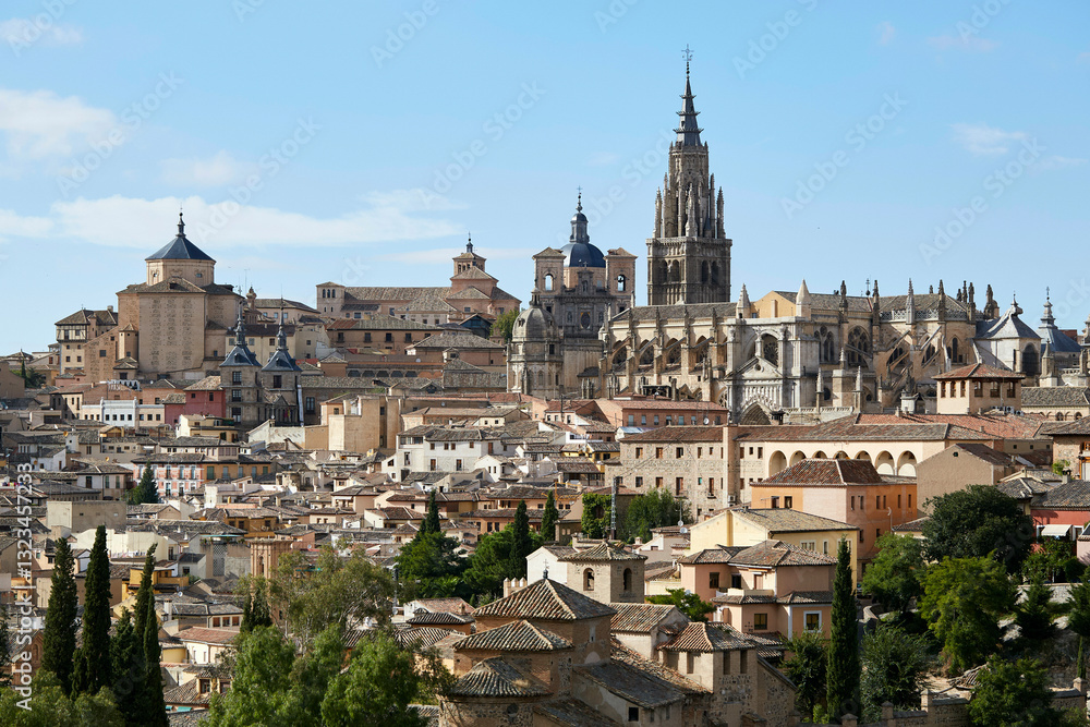 View of Toledo, Spain, showcasing historic buildings and the Toledo Cathedral against a blue sky. Toledo, Spain View of Toledo, Spain, showcasing historic buildings and the Toledo Cathedral against a blue sky. Toledo, Spain