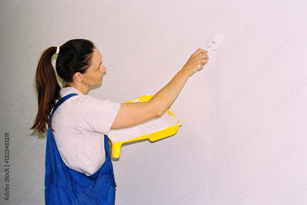 Portrait of woman painting the walls with a brush in a milky color. Portrait of woman painting the walls with a brush in a milky color.