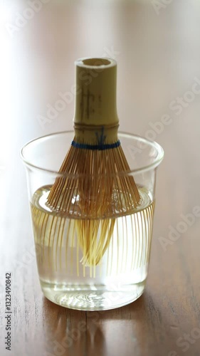 Closeup of Chasen or Bamboo whisk, an equipment for preparing matcha green tea warming in warm water showing its tip untangle.  4K. Timelapse