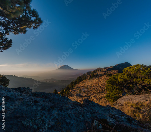 Popocatepetl volcano erupting smoke over mexican landscape at dusk photo