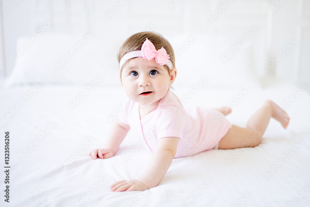 a six-month-old baby learns to crawl on a white cotton bed at home, a cute little baby girl in a pink bodysuit smiles and rejoices, close-up a six-month-old baby learns to crawl on a white cotton bed at home, a cute little baby girl in a pink bodysuit smiles and rejoices, close-up