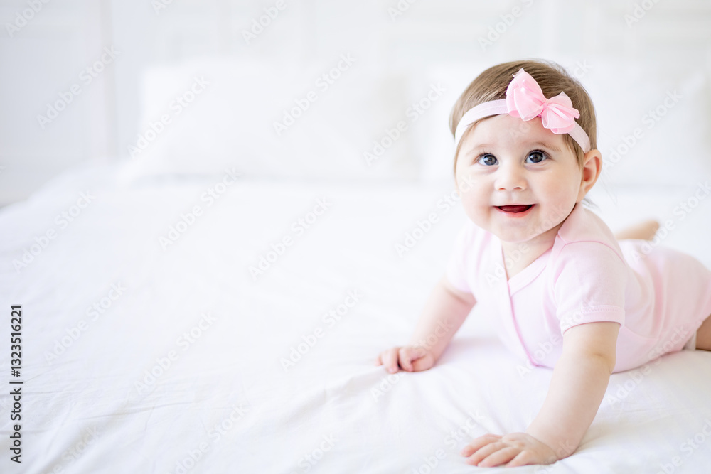 a six-month-old baby learns to crawl on a white cotton bed at home, a cute little baby girl in a pink bodysuit smiles and rejoices, close-up a six-month-old baby learns to crawl on a white cotton bed at home, a cute little baby girl in a pink bodysuit smiles and rejoices, close-up