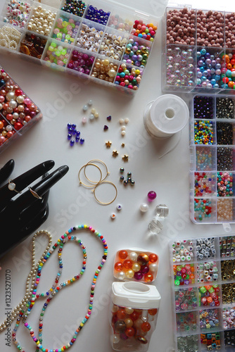 Obraz na płótnie Hand figurine, colorful friendship bracelets, necklaces, various beads and DIY supplies on the table. Making jewelry at home. Flat lay. w salonie