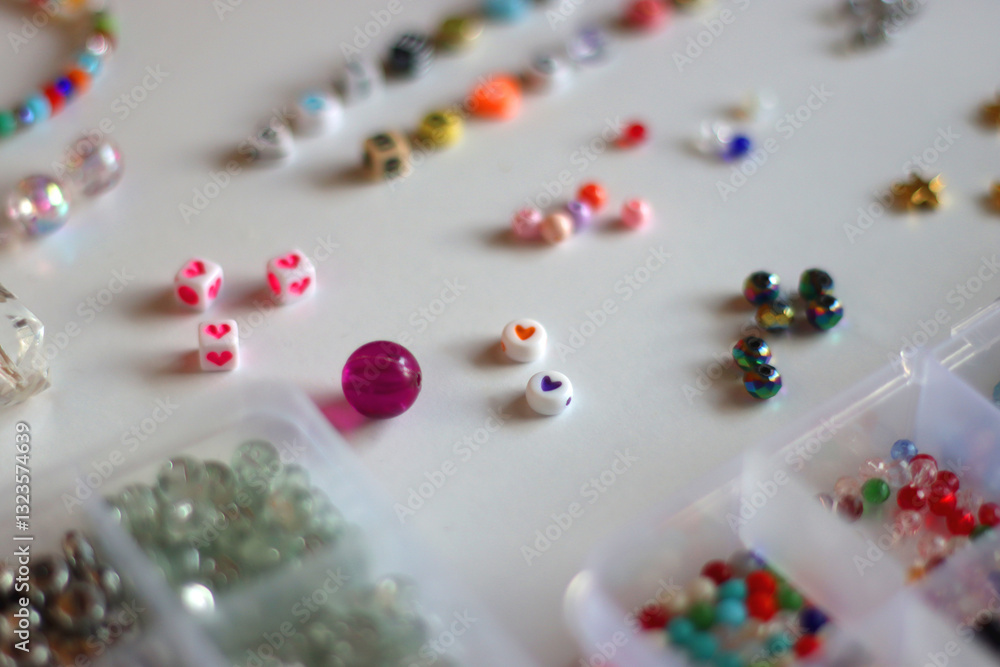 Friendship bracelet spelled with letter beads. Colorful handmade bracelets and various jewelry making supplies. Selective focus, white background.