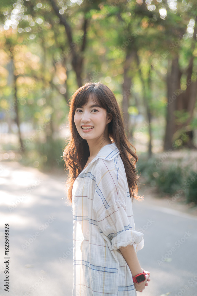 Asian woman enjoying summer day, breathing fresh air in serene park, surrounded by sunlight and greenery, with cheerful expression Asian woman enjoying summer day, breathing fresh air in serene park, surrounded by sunlight and greenery, with cheerful expression