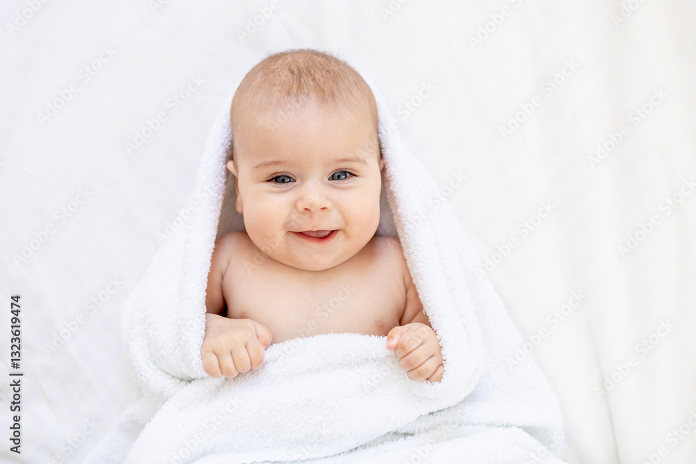 cute little newborn baby with blue eyes on the bed in a white towel after bathing or washing, happy baby at home on a cotton bed smiling cute little newborn baby with blue eyes on the bed in a white towel after bathing or washing, happy baby at home on a cotton bed smiling