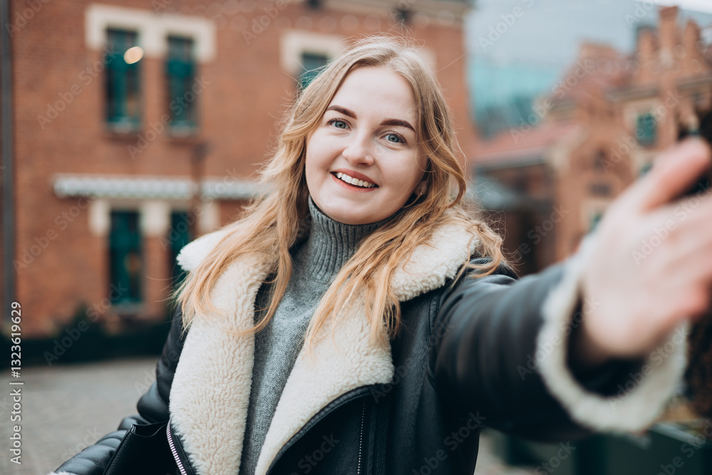 Beautiful woman in good mood looks into camera and takes selfie in the street. Blogging, technology, lifestyle, travel, tourism, active life. Winter time