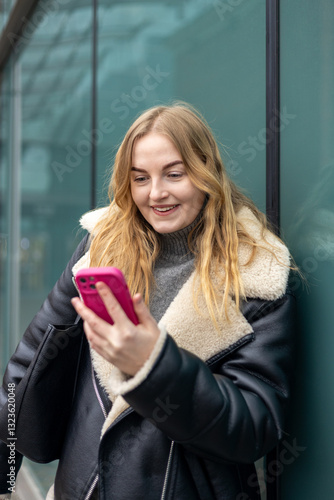 Obraz na płótnie Young stylish 30s woman writes message on smartphone walking on city street. Urban lifestyle concept. Autumn time. Charming female wearing stylish outfit chatting online. High quality photo. w salonie