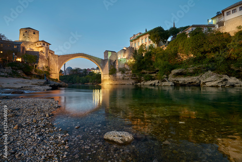 Bosnia and Herzegovina, Mostar, Old bridge in a golden sunsetting light with the green crystal clear Neretva river 