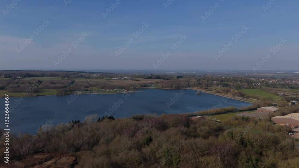Aerial view over large inland lake reservoir water sports and management of resources drinking supply in the UK Europe on a sunny day. blue waters and green landscape in winter. Aerial view over large inland lake reservoir water sports and management of resources drinking supply in the UK Europe on a sunny day. blue waters and green landscape in winter.