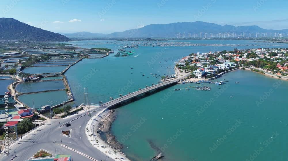 Bridge Over Crystal-Clear Waters surrounded by a city, fishing farms and mountainous wind turbines Bridge Over Crystal-Clear Waters surrounded by a city, fishing farms and mountainous wind turbines