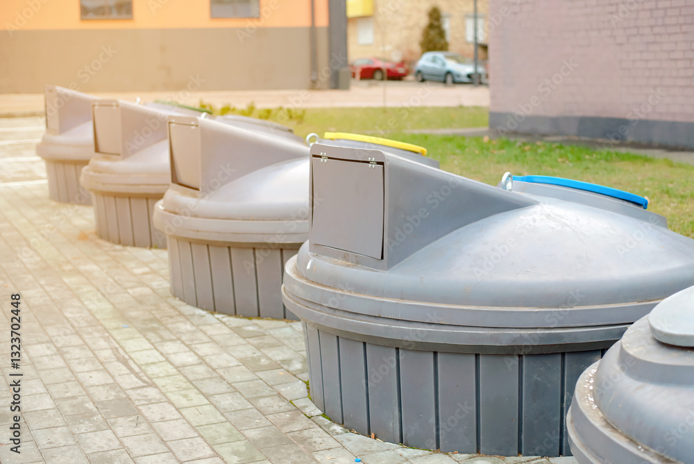 Row of modern underground trash bins with cylindrical containers designed for efficient waste management, improving urban sanitation, sustainability, and space-saving garbage disposal solutions.