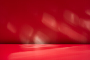 Empty table on dark red wall background. Composition with abstract shadow on the wall and pink table. Mock up for presentation, branding products, cosmetics, food or jewelry.	

