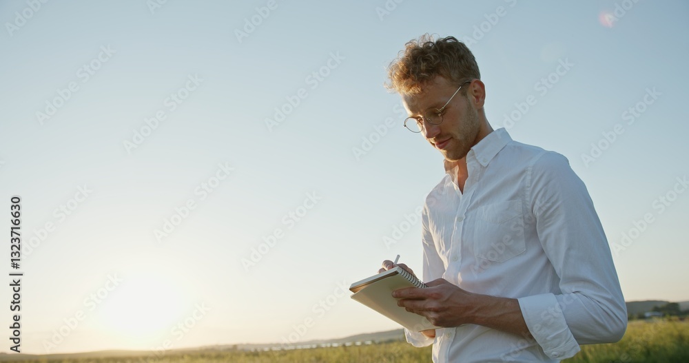 A Thoughtful Man Writing in the Great Outdoors Surrounded by Nature During a Beautiful Sunset A Thoughtful Man Writing in the Great Outdoors Surrounded by Nature During a Beautiful Sunset