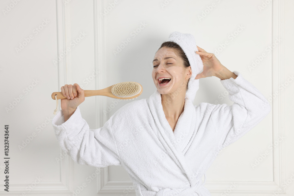 Spa day. Beautiful woman with face mask and brush singing indoors Spa day. Beautiful woman with face mask and brush singing indoors