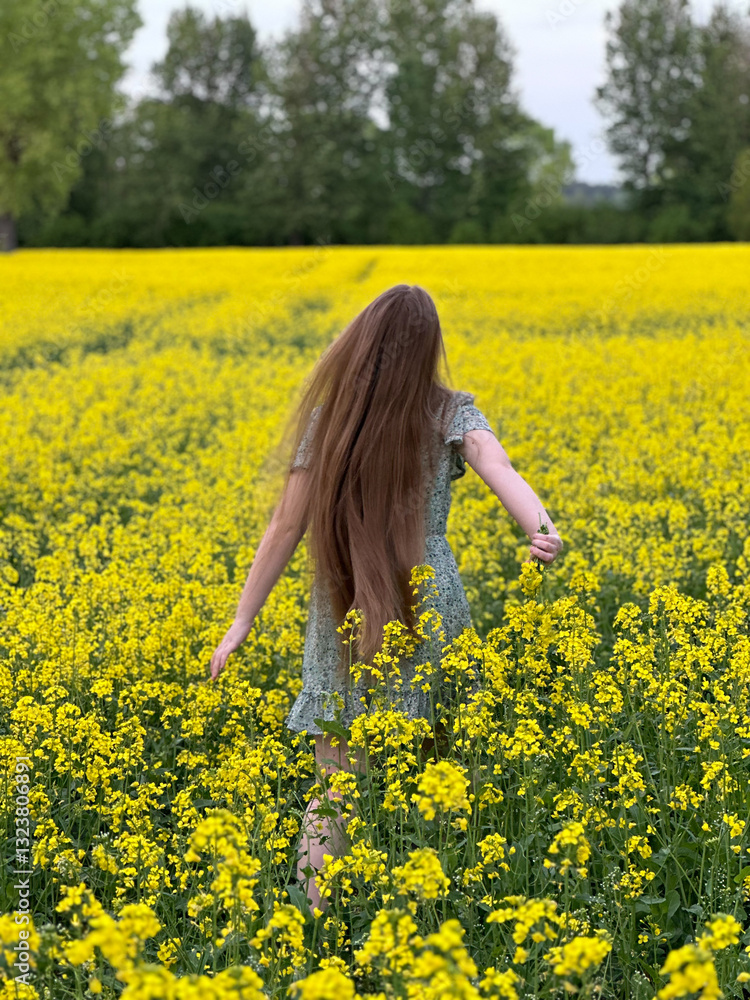 A girl with long hair runs through a yellow blooming rapeseed field A girl with long hair runs through a yellow blooming rapeseed field