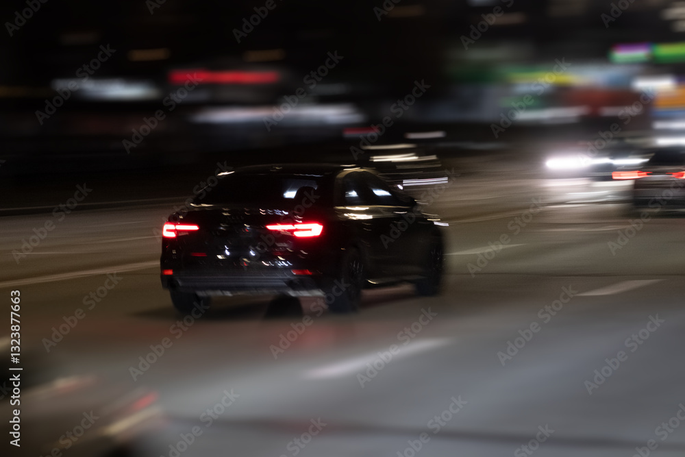 Fototapeta premium A sleek and polished black car speeds through a vibrant and illuminated city highway at night, showcasing the exhilarating thrill of urban driving under the dazzling bright lights of the metropolis