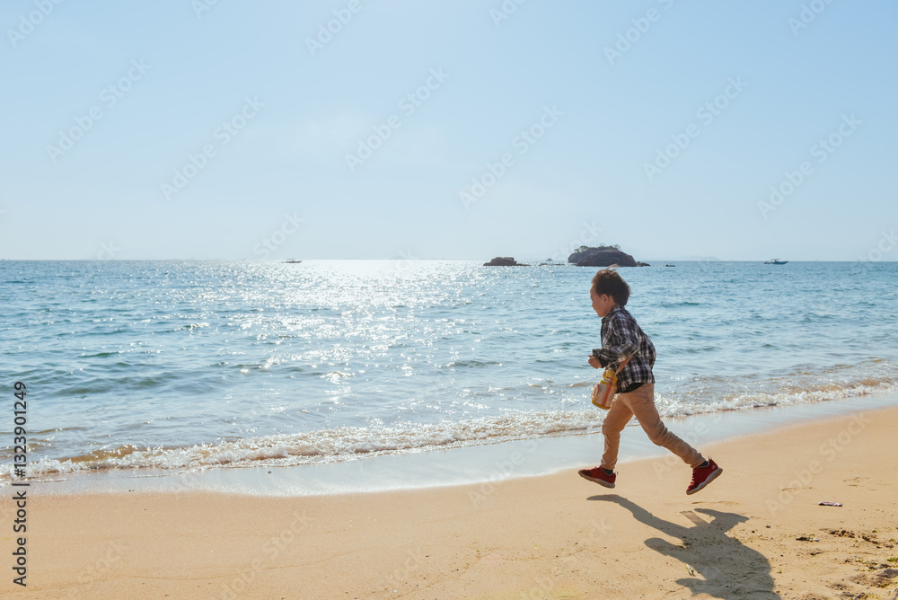 One Asian boy having fun at Xunliao Bay beach in Huizhou, Guangdong province, China, in January winter One Asian boy having fun at Xunliao Bay beach in Huizhou, Guangdong province, China, in January winter