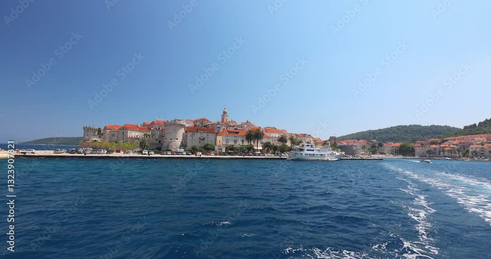 Korcula town in island of Korcula in Adriatic sea in Croatia, Europe. Coastal town with old stone buildings, towers and red rooftops on a sunny day, viewed from the ocean with a clear blue sky above. Korcula town in island of Korcula in Adriatic sea in Croatia, Europe. Coastal town with old stone buildings, towers and red rooftops on a sunny day, viewed from the ocean with a clear blue sky above.
