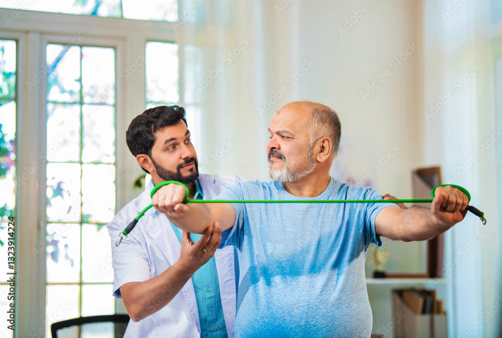 Indian physiotherapist guiding senior man with shoulder pain through resistance band exercises Indian physiotherapist guiding senior man with shoulder pain through resistance band exercises