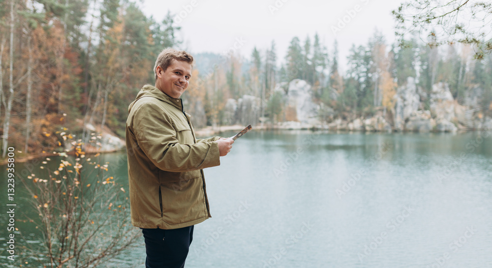 Travel backpacker standing with paper map near the majestic lake. Travel, adventure, people banner. Concept of an active lifestyle. High quality photo. Rear view