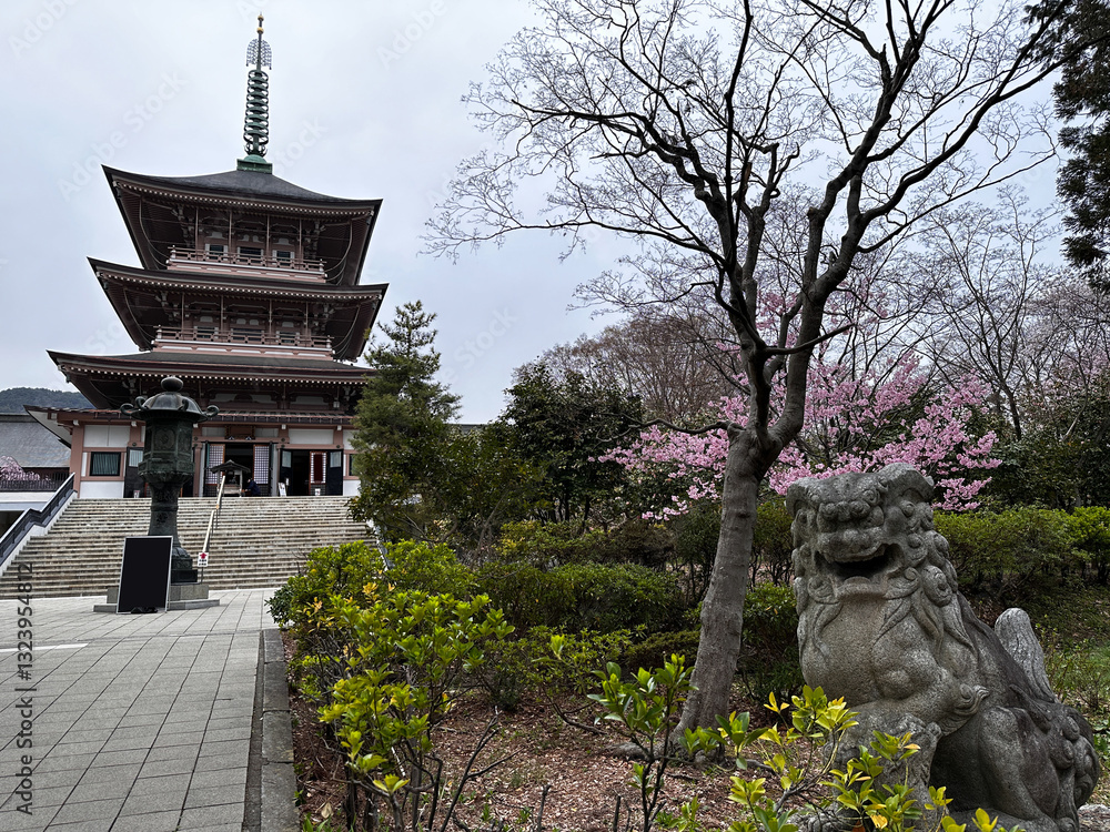 Traditional Japanese Pagoda with Guardian Statue and Cherry Blossoms