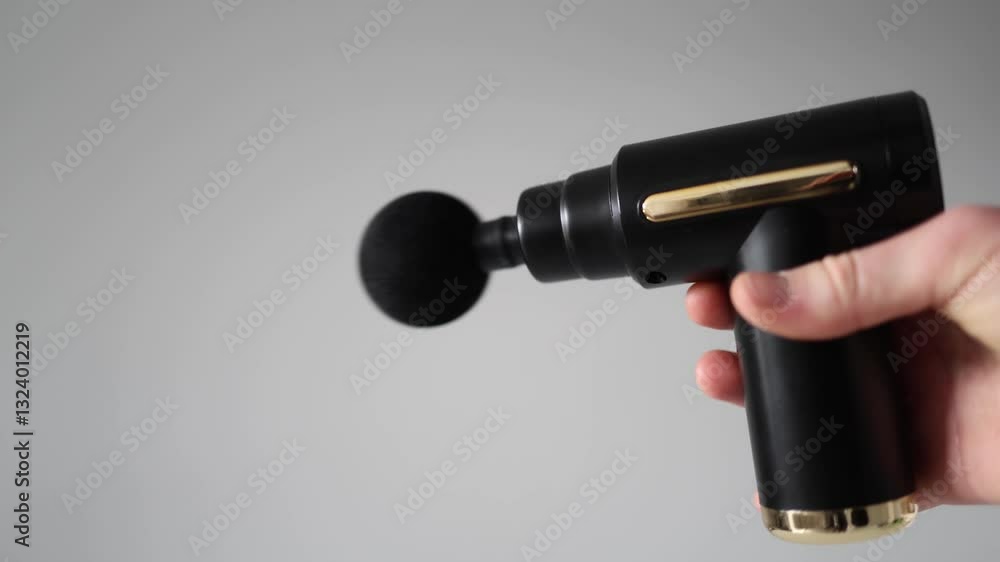 Massage gun in action, held in a hand against a neutral background. The device vibrates rapidly, highlighting its ergonomic design and therapeutic function for muscle relaxation and recovery. Massage gun in action, held in a hand against a neutral background. The device vibrates rapidly, highlighting its ergonomic design and therapeutic function for muscle relaxation and recovery.