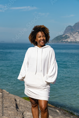 Portrait of a confident young woman in white blouse with blue sea view on the background. 