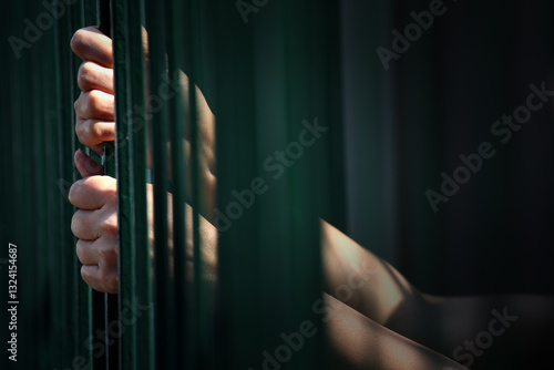 Fotografie Hands Gripping Metal Bars in Dim Light Illustrating Confinement