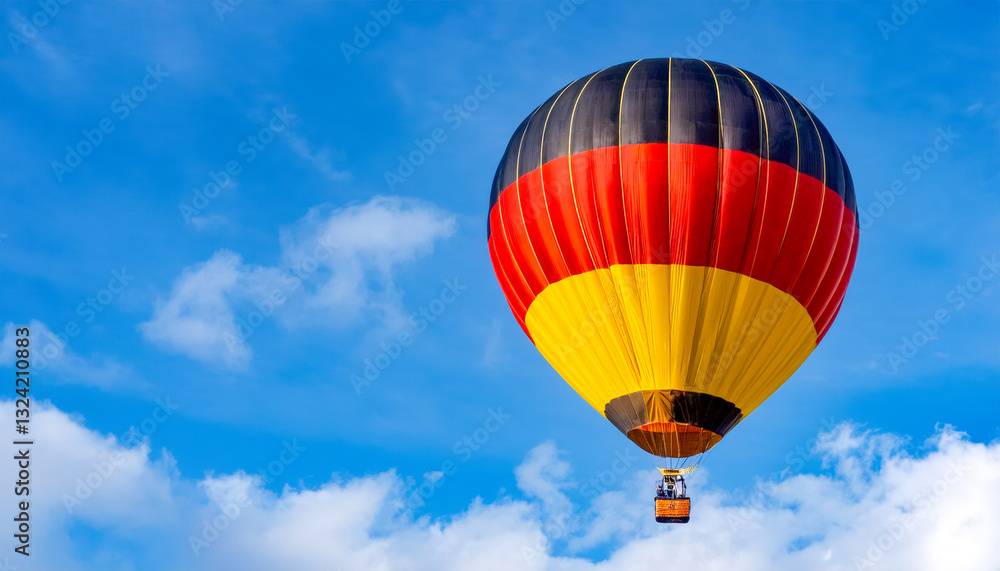 Fototapeta premium Colorful hot air balloon floats against a clear blue sky in a vibrant display of yellow, black, and red