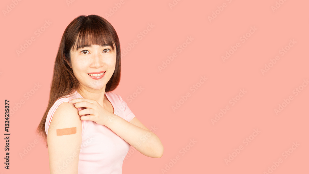 Asian woman showing vaccinated arm with medical adhesive bandage strip after vaccine injection over pink background. Concept of HPV vaccine, world immunization day and vaccinations in pregnancy. Asian woman showing vaccinated arm with medical adhesive bandage strip after vaccine injection over pink background. Concept of HPV vaccine, world immunization day and vaccinations in pregnancy.