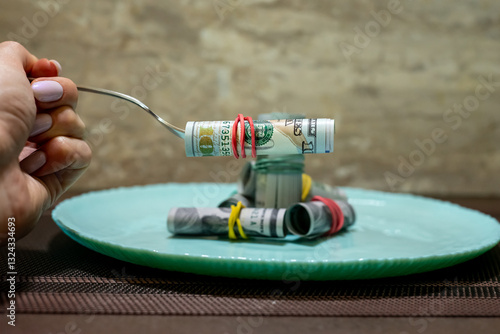Money spread out on a turquoise plate with a knife and fork nearby, food costs, price increases.